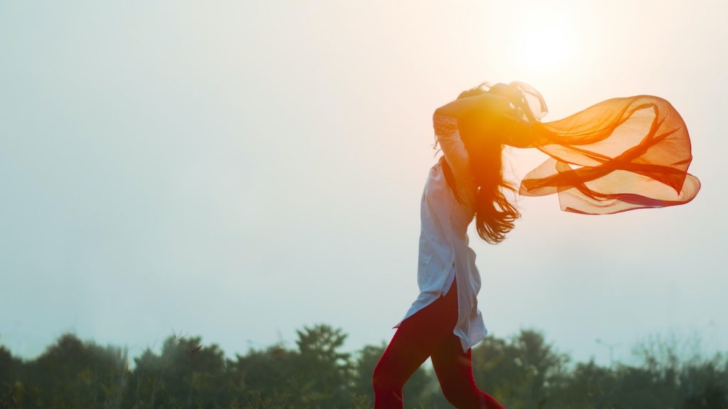 A woman with a flowing headscarf and long hair enjoying a walk on a warm evening.