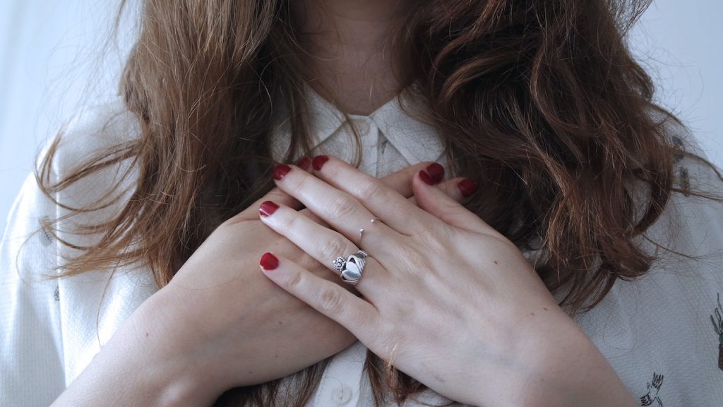 A woman with her hands crossed over her heart.