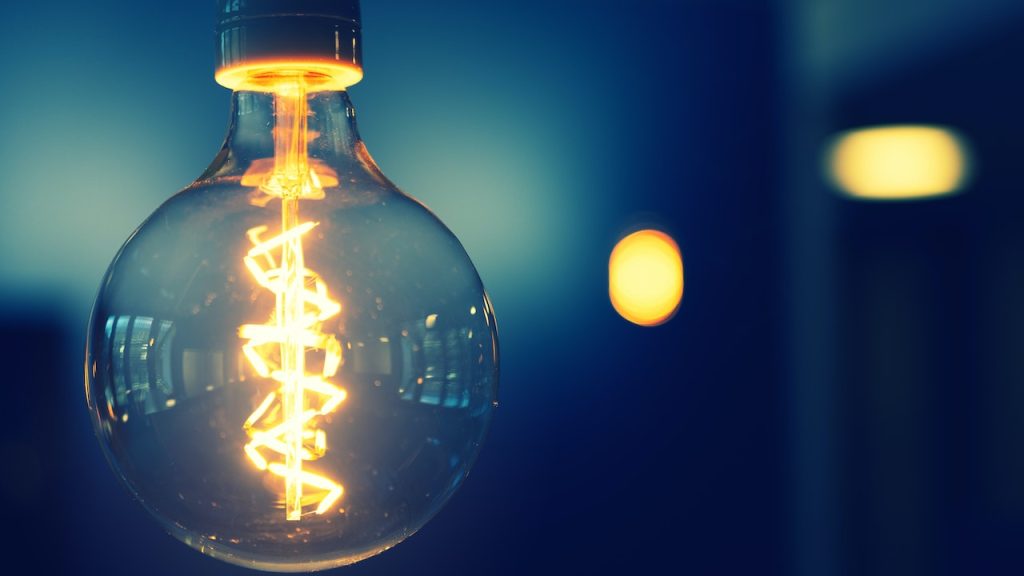 An illuminated glowing glass bulb dangling from the ceiling.