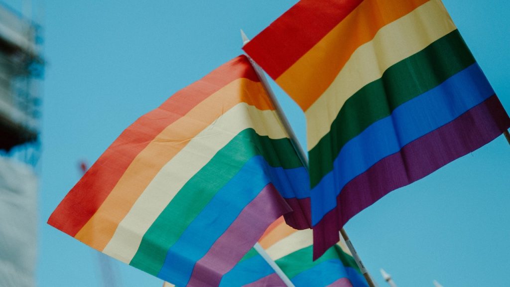 Rainbow flags waving against a blue sky.