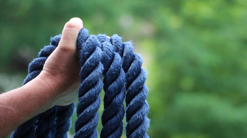 A hand holding some thick blue rope.