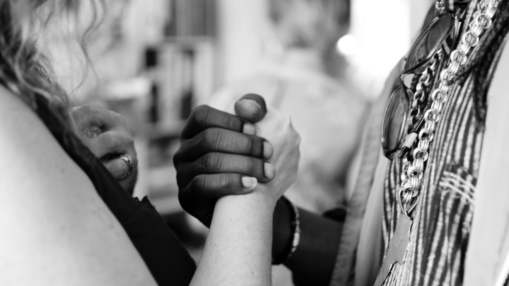 Two people with their hands clasped together in solidarity.