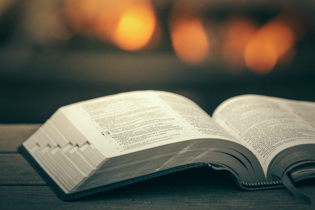 An open Bible on a wooden bench.