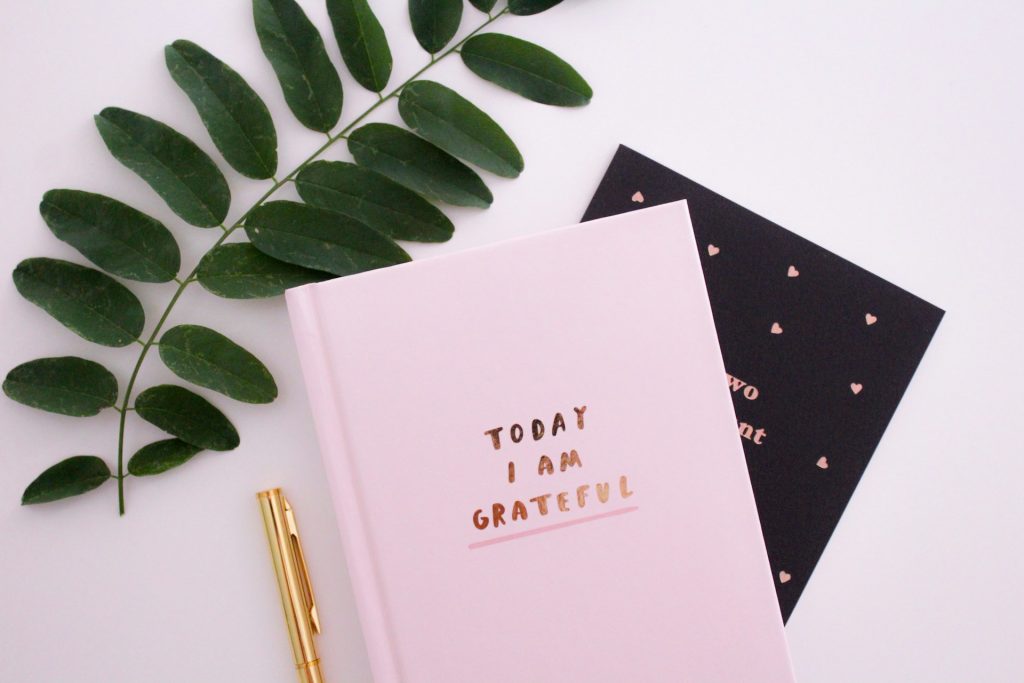 A journal on a desk embossed with the words, 'Today I am grateful'