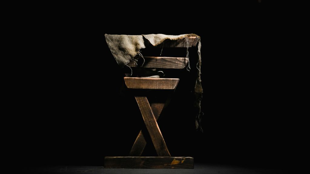 A wooden feeding trough in a dark room.