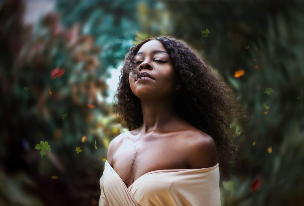 A woman with long flowing hair with her head tilted up and eyes closed looking confident and serene.