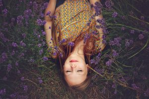 A woman lying with her eyes closed in a bed of lavender.