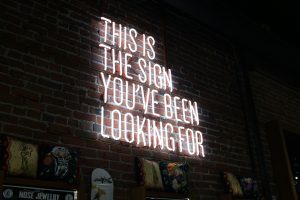 The words 'This is the sign you've been looking for' in neon on the wall of a bar.
