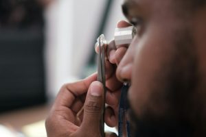 A man examines a diamond using an eyepiece.
