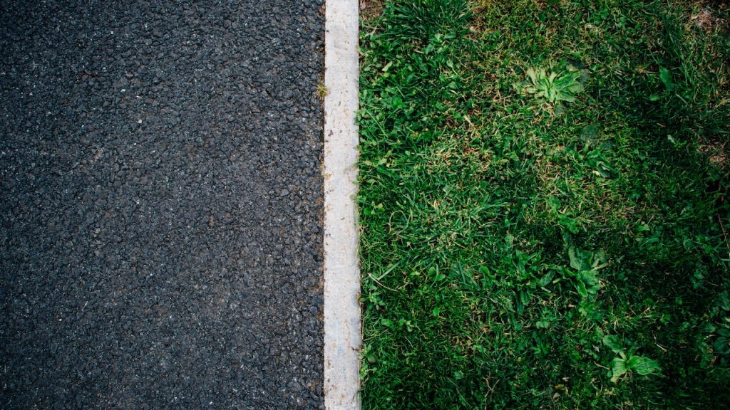 The neat white painted line of a verge between the road and some grass.