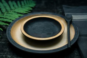 An empty bowl and spoon sit on an empty plate on a table.