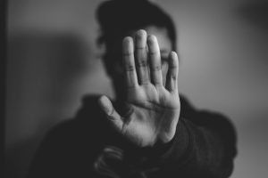 A woman holds up her hand, palm facing outwards as if to say, "Get away from me!"