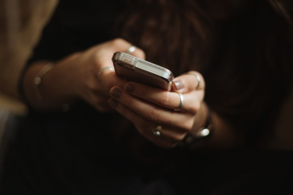 A woman with beautiful rings on her fingers holds a phone.