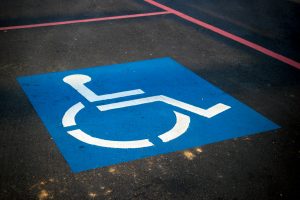 A white on blue wheelchair parking symbol painted on asphalt or tarmac.