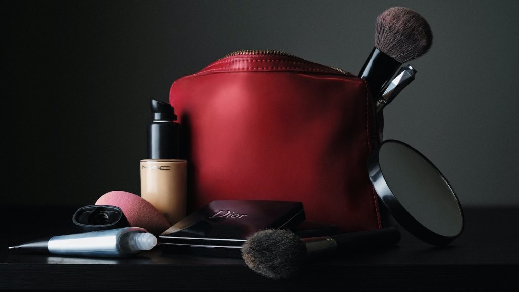 A makeup bag with brushes and bottles and a mirror.