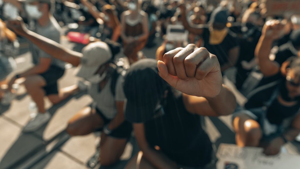 A crowd all on bended knees fist pumping the air.