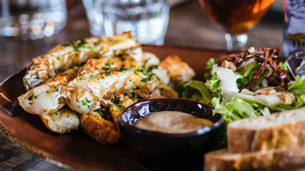 A plate of delicious looking wraps, salad, bread, and a dip.