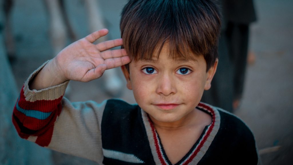 A street boy making a salute towards the camera.