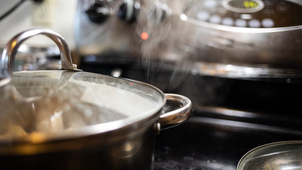 Steam escaping from the edge of a pot on a stove.