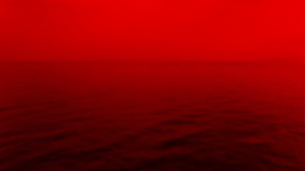 A calm sea and sky all coloured red.