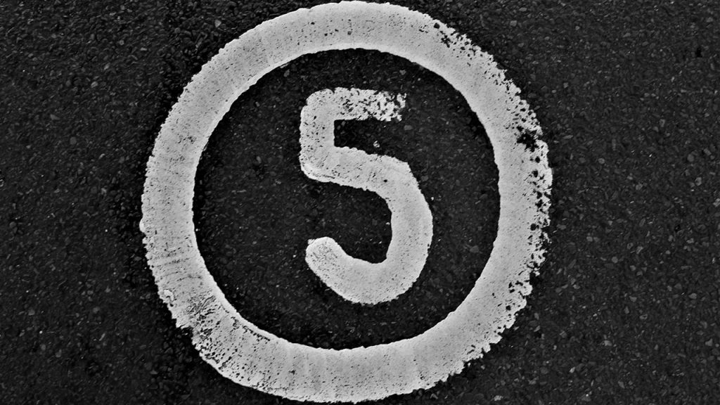 The number 5 painted and in a circle on tarmac.