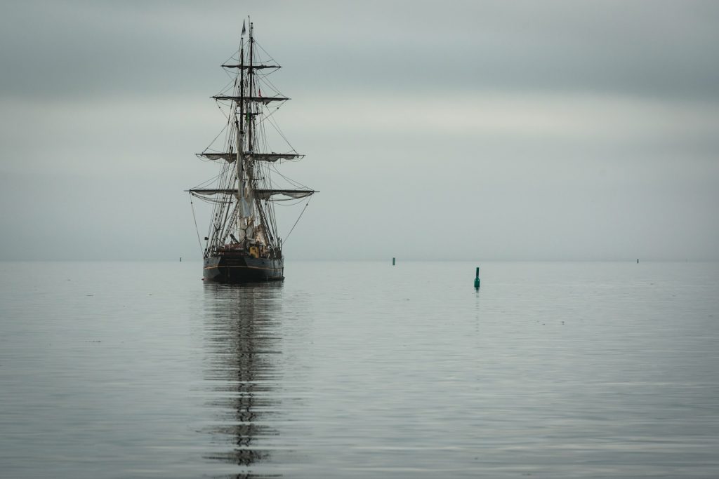 A tall ship at anchor on a calm sea.