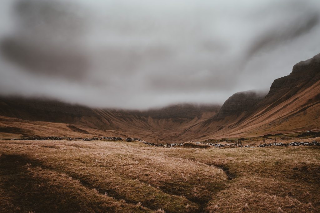 A Scottish valley surrounded by fog-capped mountains.