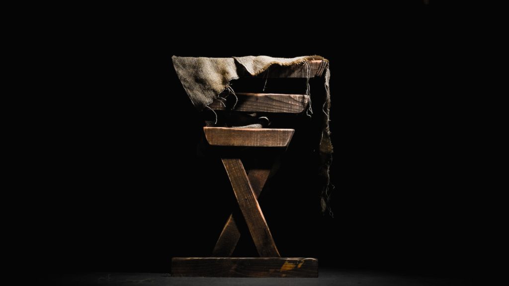 A wooden manger standing illuminated in a dark room.