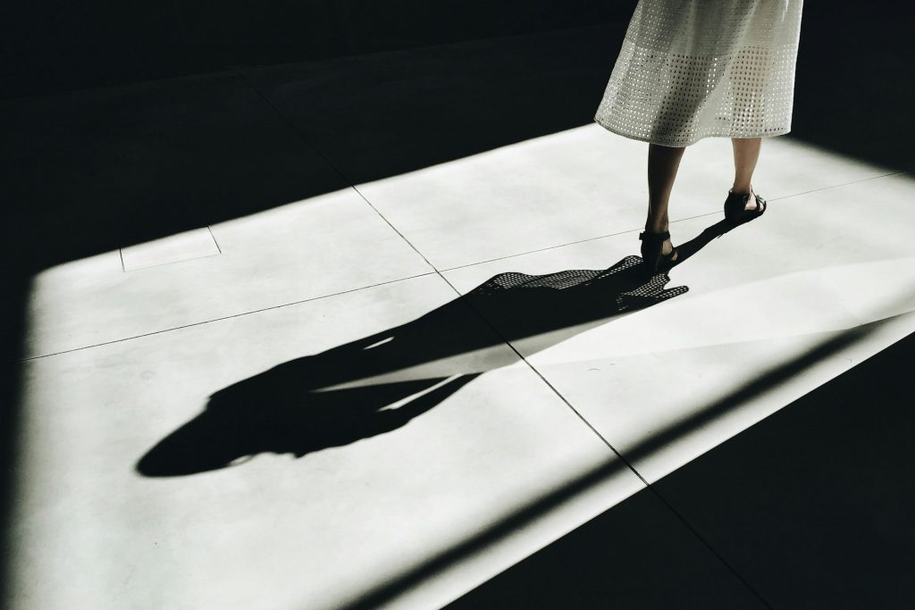 The shadow of a woman walking on a tiled floor.