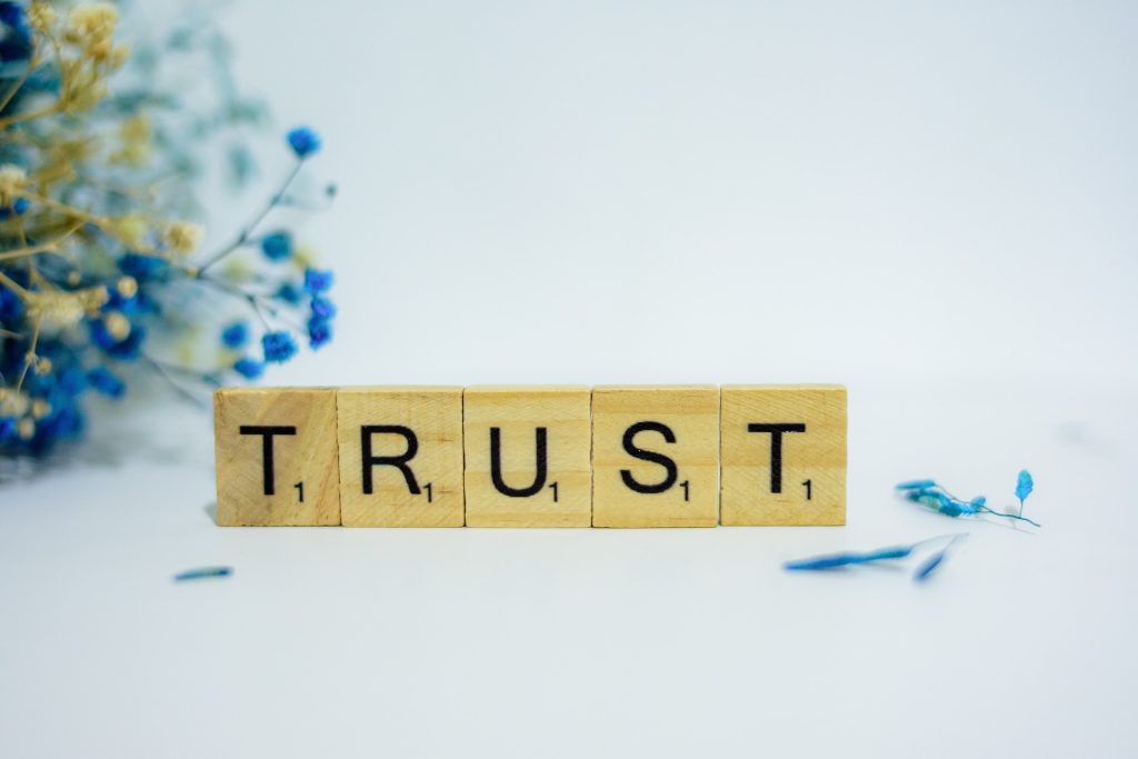 The word TRUST spelled out in wooden Scrabble tiles.