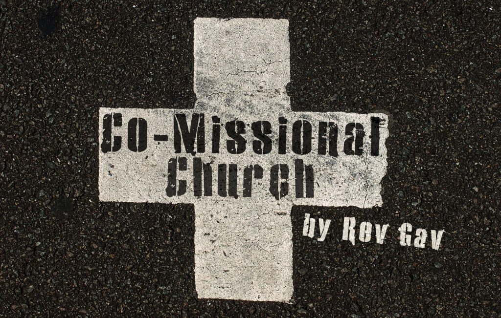 A road with a cross painted on it with the words Co-Misssional Church by Rev Gav stencilled on it.