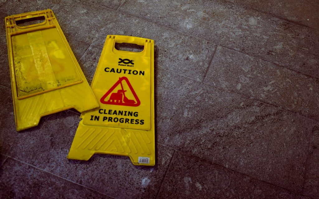 A plastic sign saying 'Caution - Cleaning in Progress' on a tiled floor.