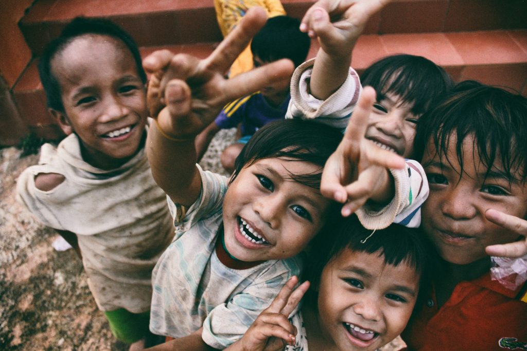 A group of happy smiling street kids all looking up towards a camera.