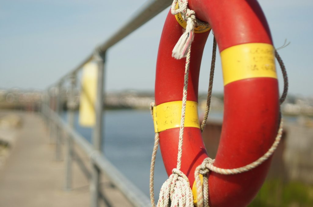 A life-ring tied to a railing next to a body of water.