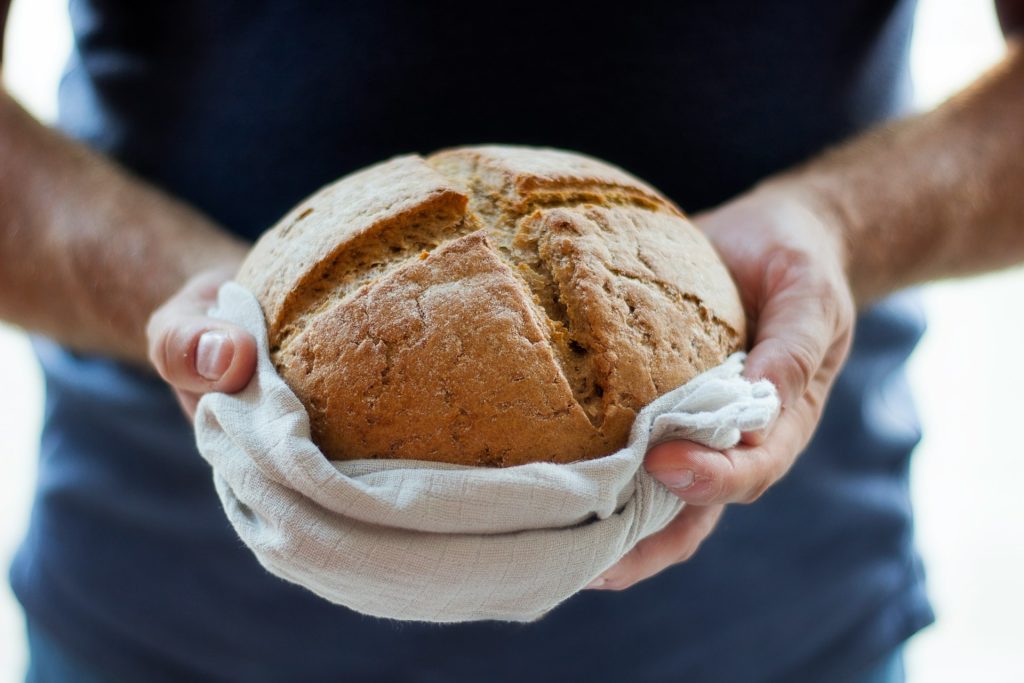 A man holding freshly baked bread in his hands.