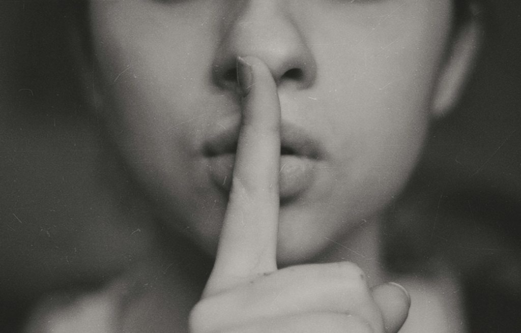 A woman with her finger pressed to her lips.