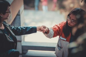 A Vietnamese women reaches out her hand to another offering her mercy.