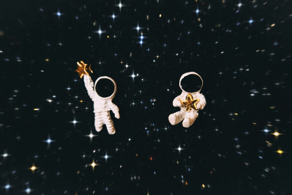 Two astronaut figurines against a starlit backdrop.