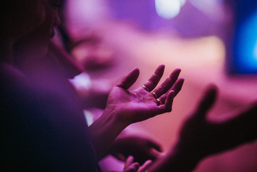 A woman holds out a hand in supplication and prayer.