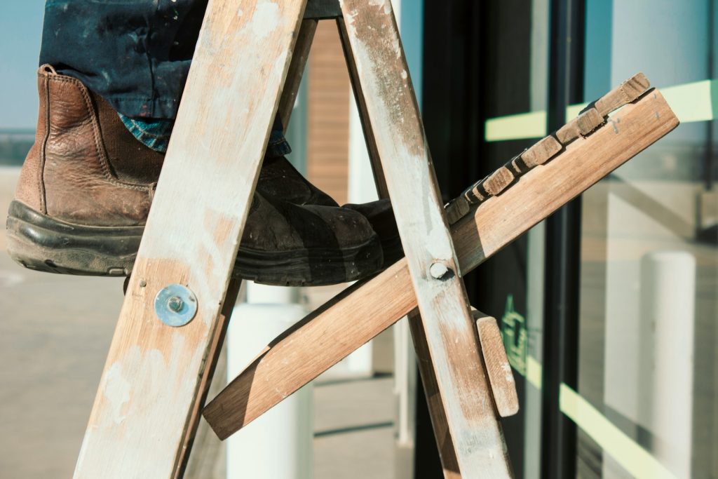 A person stands on a wooden step ladder.