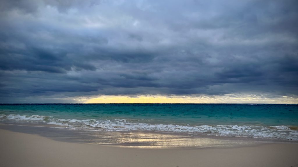 The sun shines on the ocean behind the clouds.