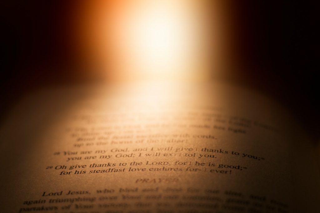 A light shines down on an open Bible, open to words from Psalm 118 which are illuminated.