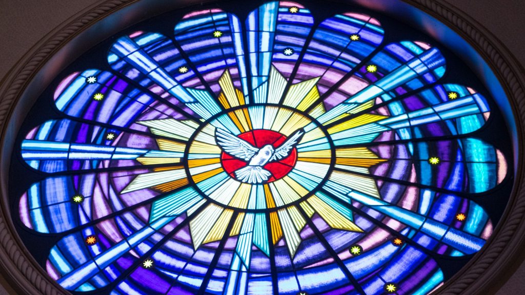 A stained glass window with a dove in the centre.