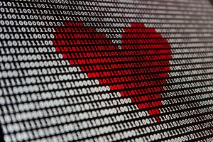 A screen is filled with white binary numbers - zeros and ones. Some of them are red and make the picture of a heart.