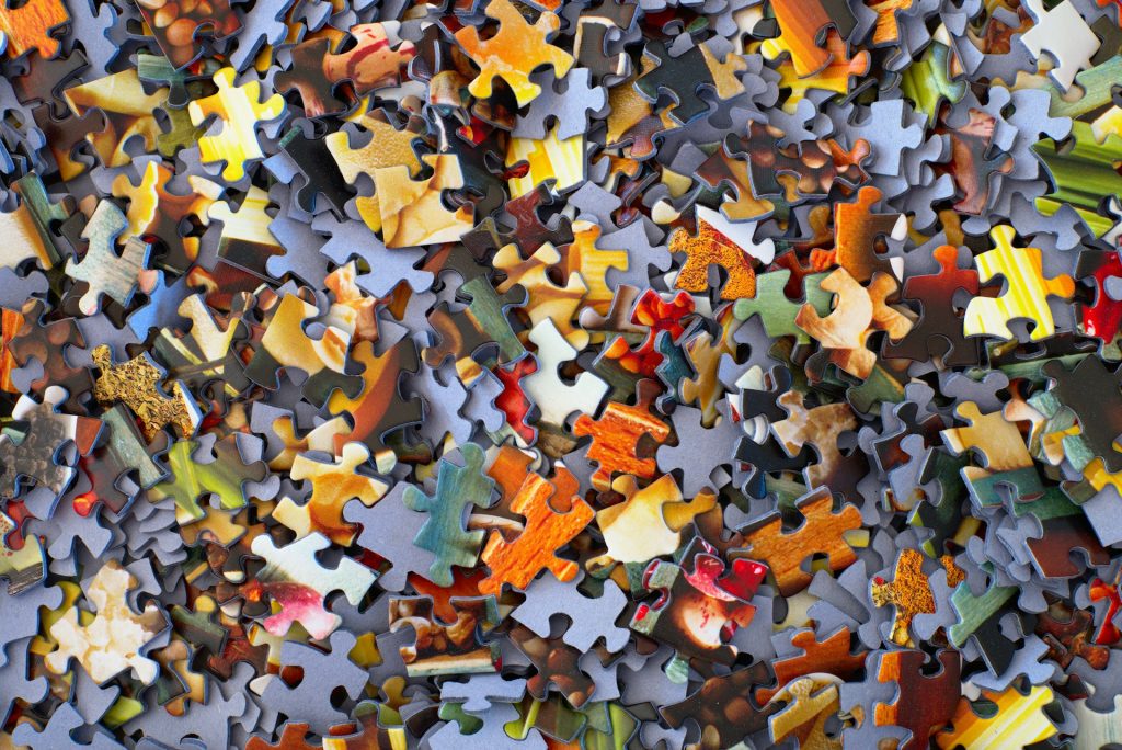 Hundreds of multicoloured pieces of jigsaw puzzle jumbled up in a box lid.