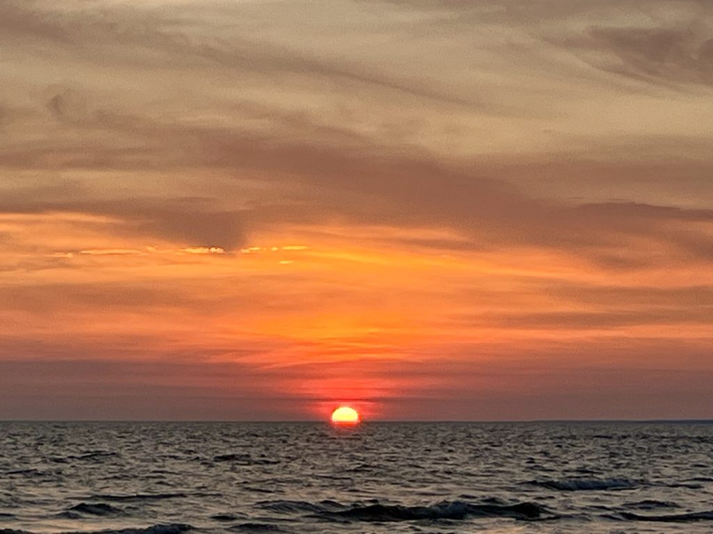 Gorgeous red sunset with a red sun on the horizon over a lake.