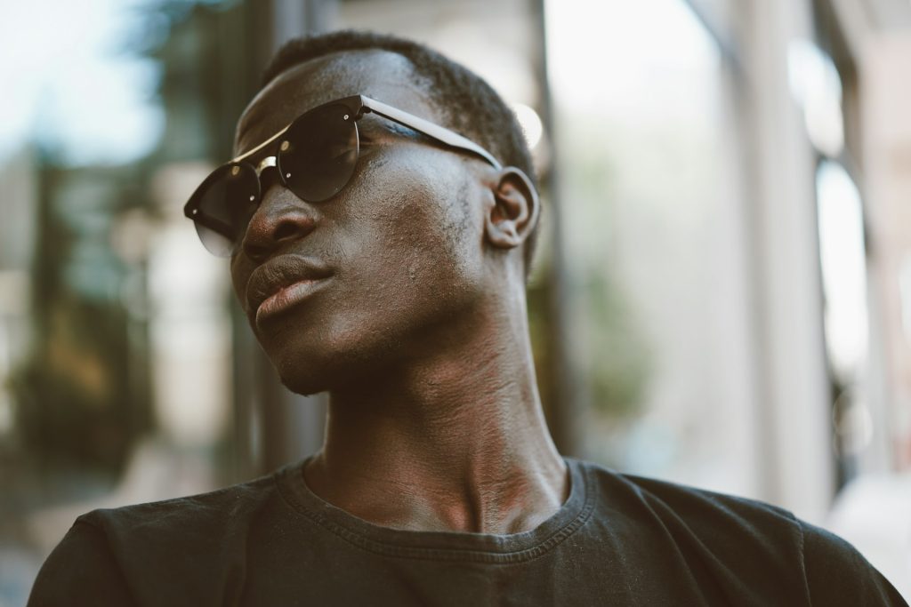 A black man wearing sunglasses and a black T-shirt looking very cool.