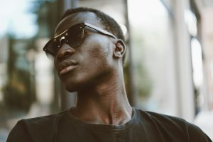 A black man wearing sunglasses and a black T-shirt looking very cool.