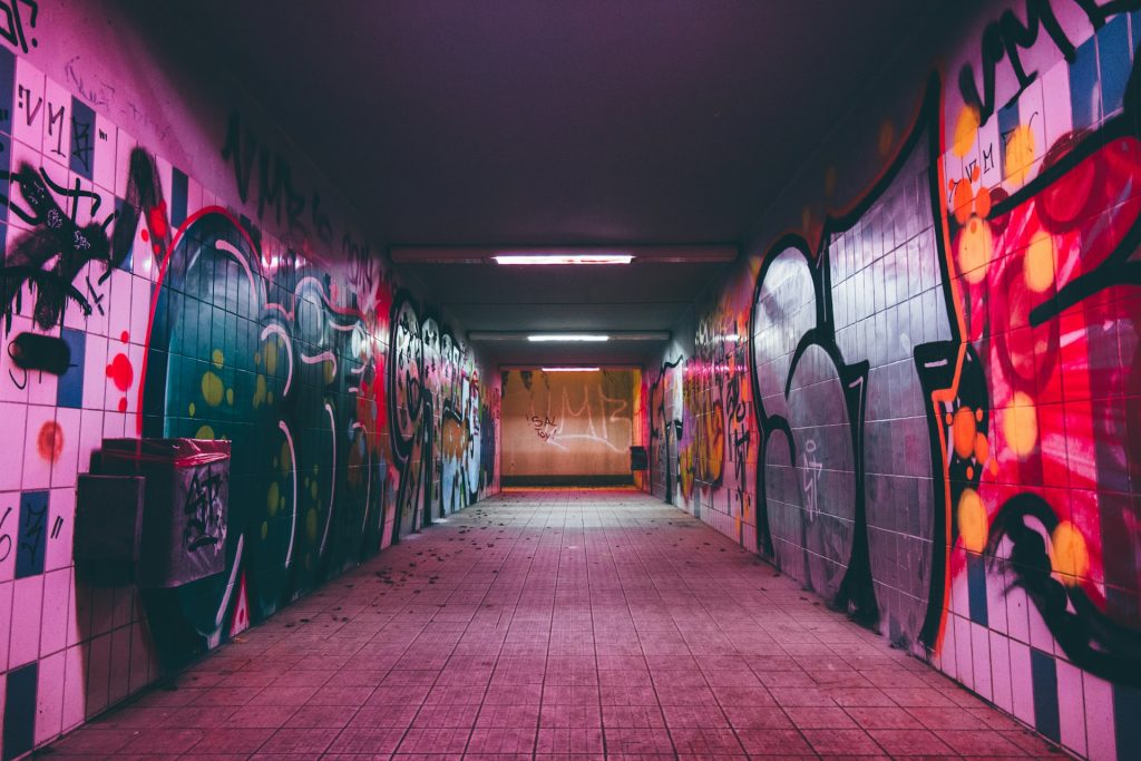How do we break free from oppressive systems? Brightly coloured graffiti on the walls of a subway.