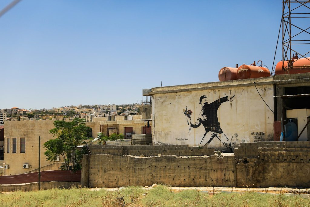What does Jesus say about resurrection? Banksy art of rebel throwing flowers like a grenade.